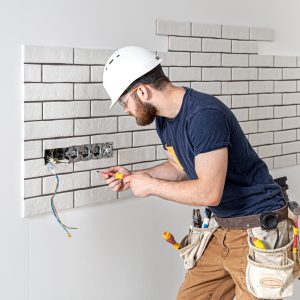 electrician-construction-worker-with-beard-overalls-installation-sockets-home-renovation-concept-min